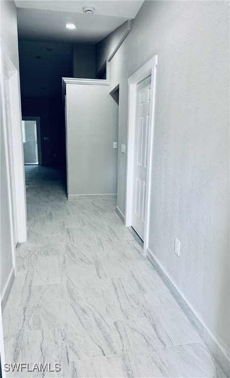 hallway with baseboards and marble finish floor