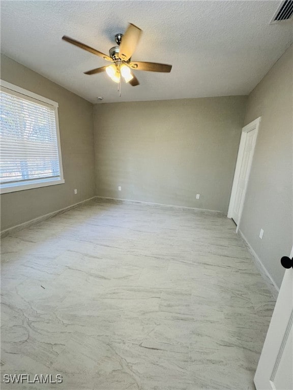 empty room featuring visible vents, ceiling fan, a textured ceiling, and baseboards