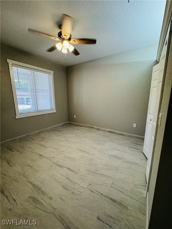 unfurnished bedroom with a textured ceiling, baseboards, and a ceiling fan