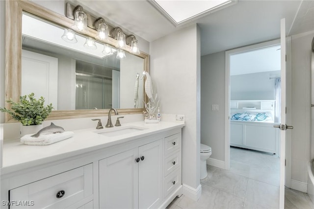 ensuite bathroom featuring ensuite bathroom, toilet, a shower with shower door, vanity, and baseboards