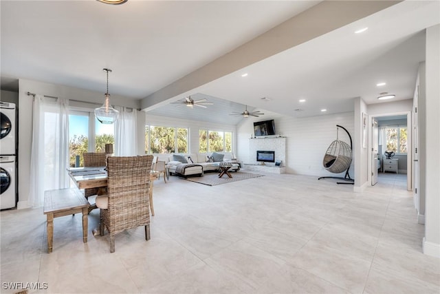 dining area featuring stacked washer and dryer, baseboards, a ceiling fan, a glass covered fireplace, and recessed lighting