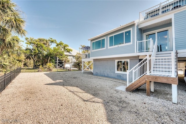 rear view of property featuring stairway, gravel driveway, and fence