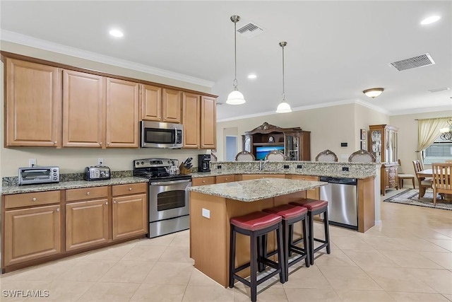 kitchen with crown molding, a breakfast bar area, stainless steel appliances, a center island, and kitchen peninsula