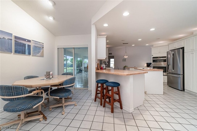 kitchen featuring hanging light fixtures, a kitchen breakfast bar, kitchen peninsula, stainless steel appliances, and white cabinets