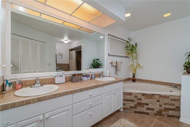 bathroom with a relaxing tiled tub, tile patterned floors, and vanity