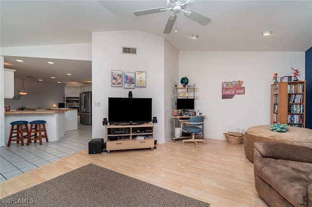 living room with vaulted ceiling, ceiling fan, and light wood-type flooring