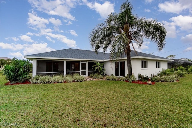 rear view of house featuring a sunroom and a lawn