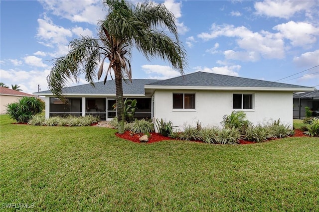 rear view of house featuring a yard and a sunroom