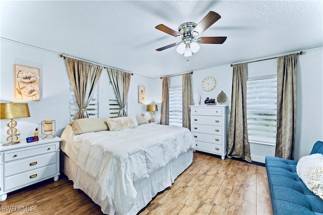 bedroom with a textured ceiling, multiple windows, and light hardwood / wood-style flooring