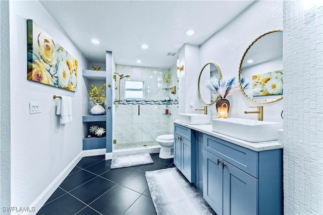 bathroom with tile patterned flooring, a tile shower, vanity, a textured ceiling, and toilet