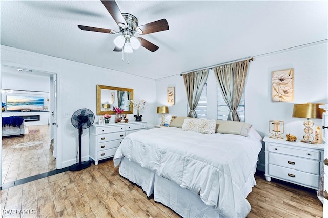 bedroom with ceiling fan, a textured ceiling, and light wood-type flooring