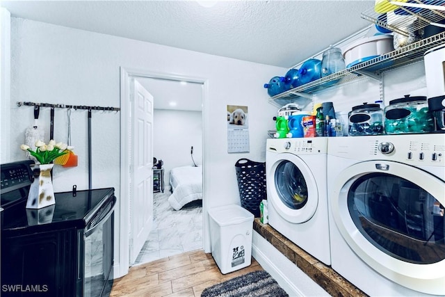 clothes washing area with wood-type flooring, washer and dryer, and a textured ceiling