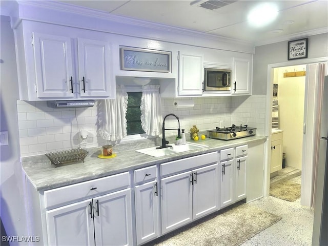 kitchen featuring white cabinetry, sink, and tasteful backsplash