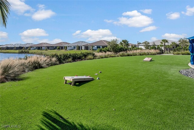 surrounding community with a water view and a yard