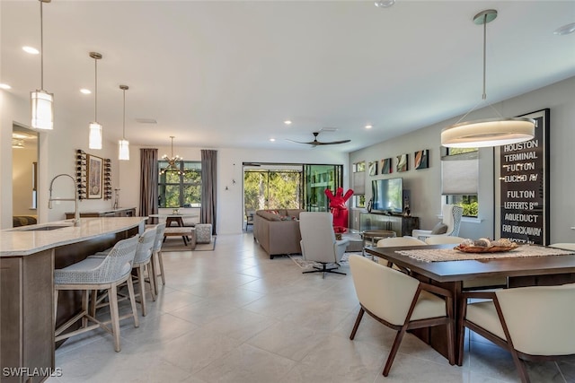 tiled dining room with sink and ceiling fan with notable chandelier