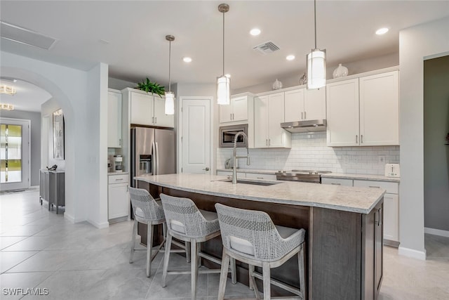 kitchen featuring stainless steel appliances, a kitchen island with sink, sink, and white cabinets