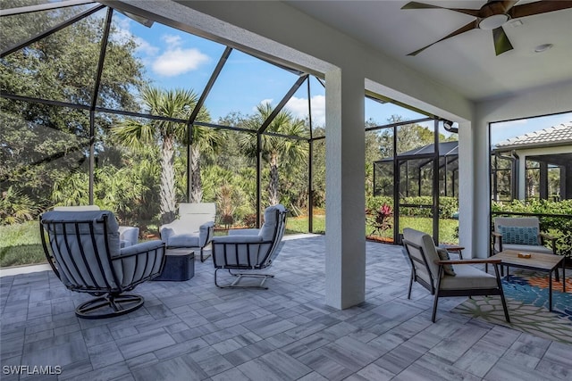 view of patio featuring outdoor lounge area, ceiling fan, and glass enclosure