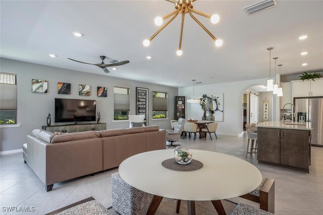 living room with ceiling fan with notable chandelier and light tile patterned floors