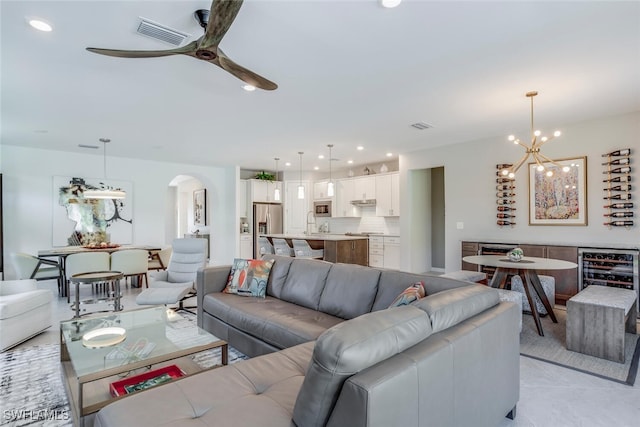 tiled living room with ceiling fan with notable chandelier