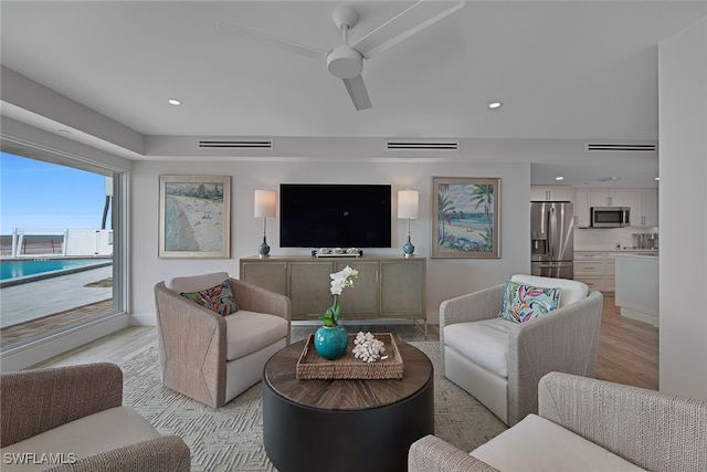 living room with ceiling fan and light hardwood / wood-style flooring