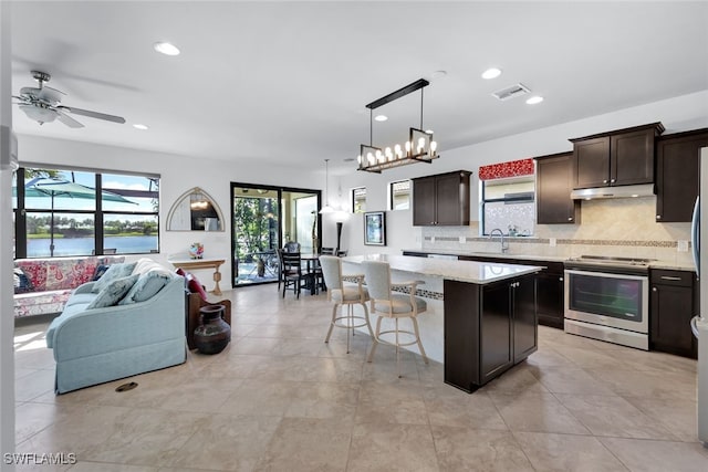 kitchen featuring sink, stainless steel electric range, hanging light fixtures, a water view, and a kitchen island