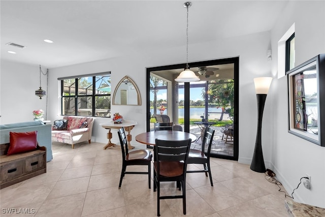 dining room with light tile patterned floors and a water view