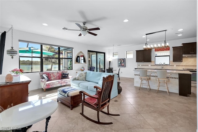 tiled living room featuring a water view, sink, and ceiling fan