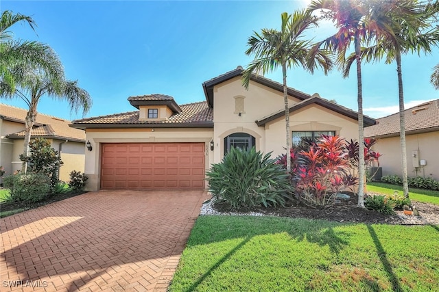 mediterranean / spanish-style house featuring an attached garage, a front yard, decorative driveway, and stucco siding