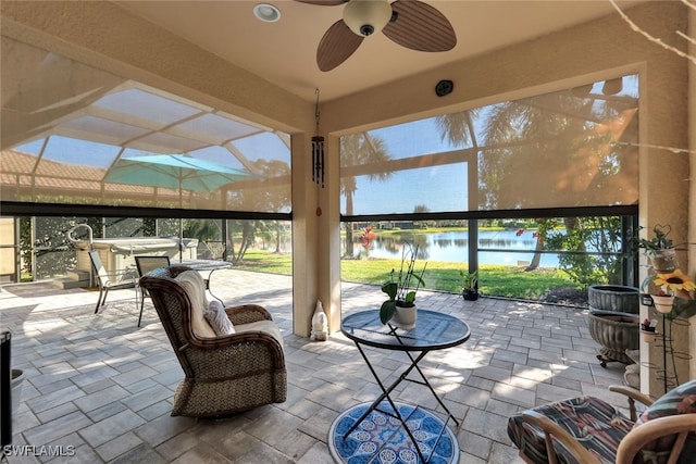 sunroom / solarium featuring a water view and ceiling fan