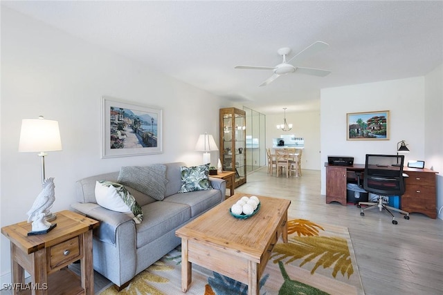 living room featuring ceiling fan with notable chandelier and light wood-type flooring