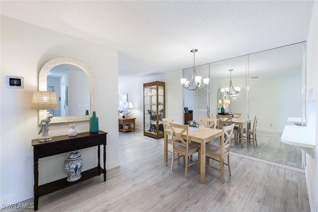 dining area featuring a chandelier, a textured ceiling, and light wood-type flooring