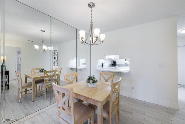 dining area featuring light wood-type flooring, a textured ceiling, and a notable chandelier