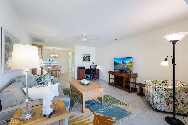 living room featuring ceiling fan with notable chandelier and light hardwood / wood-style floors