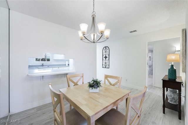 dining space featuring sink, a chandelier, and light hardwood / wood-style floors