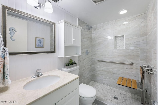 bathroom featuring vanity, a tile shower, and toilet