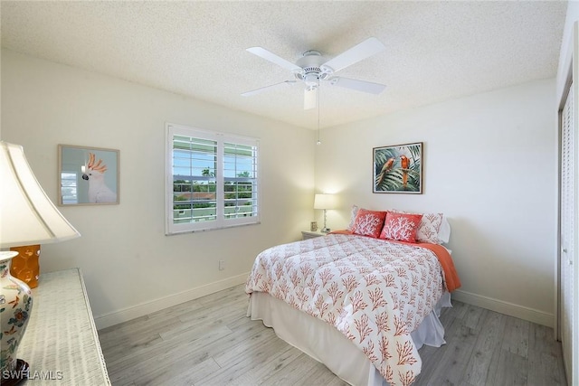 bedroom featuring light hardwood / wood-style floors, a textured ceiling, ceiling fan, and a closet