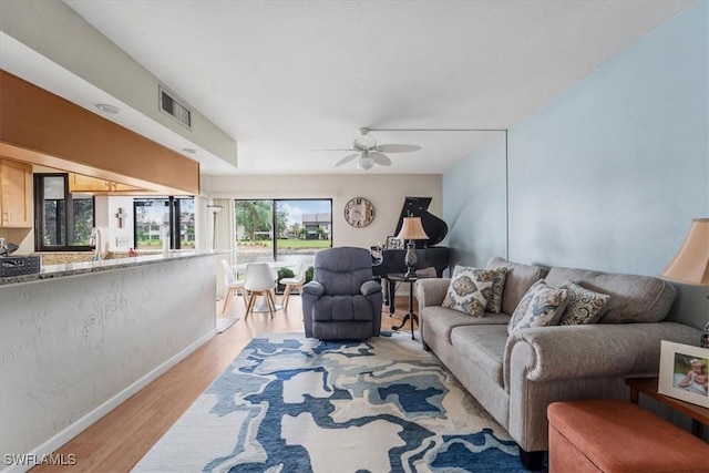 living room featuring ceiling fan, sink, and light wood-type flooring