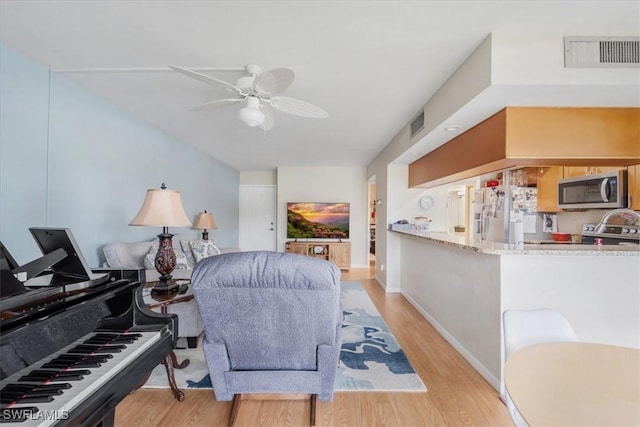 living room with ceiling fan and light hardwood / wood-style floors