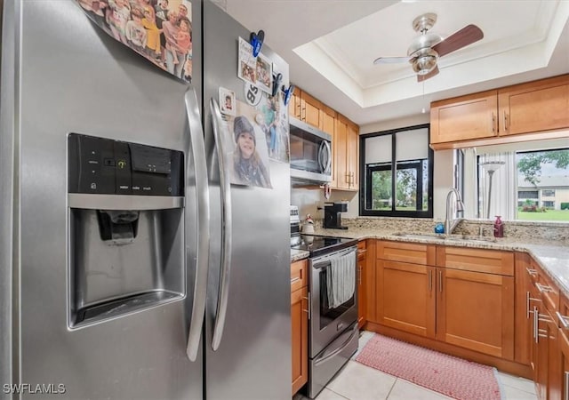 kitchen with light stone counters, sink, a raised ceiling, and appliances with stainless steel finishes