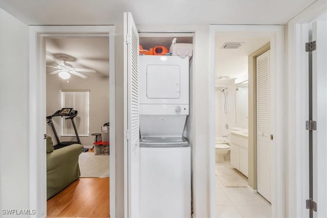 laundry area featuring stacked washer and dryer, ceiling fan, and light hardwood / wood-style floors