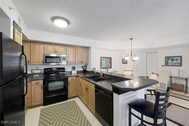 kitchen featuring a breakfast bar, a peninsula, a sink, black appliances, and dark countertops