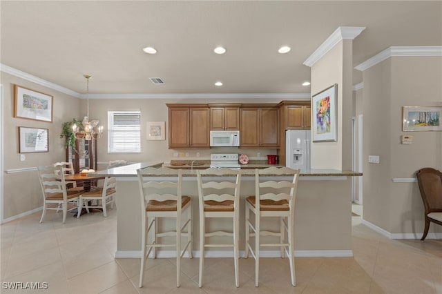 kitchen with a kitchen bar, a center island with sink, light stone counters, and white appliances