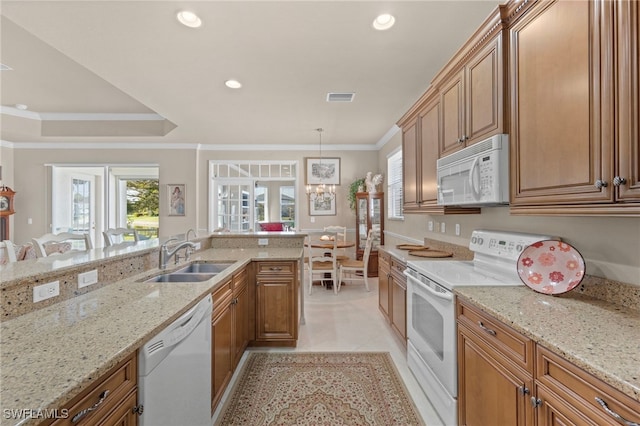 kitchen featuring sink, light stone counters, hanging light fixtures, ornamental molding, and white appliances