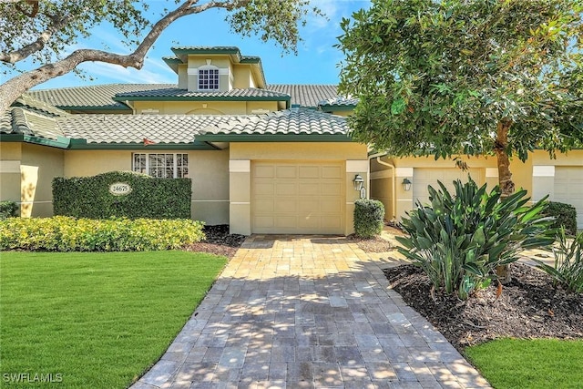 mediterranean / spanish home featuring a garage and a front lawn