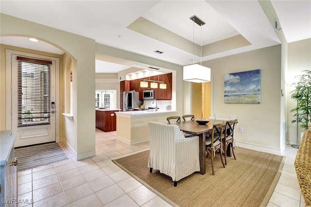 dining area with a raised ceiling and light tile patterned floors