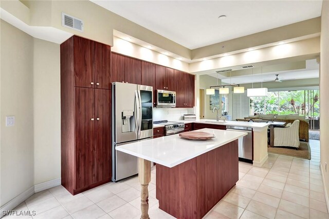 kitchen with light tile patterned floors, a kitchen island, a kitchen breakfast bar, and appliances with stainless steel finishes