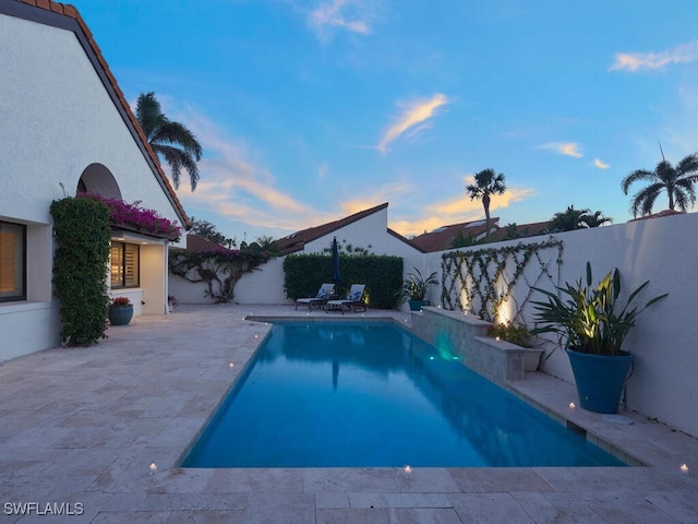 pool at dusk featuring a fenced backyard and a fenced in pool