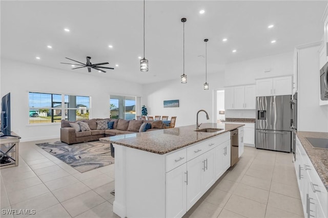 kitchen featuring an island with sink, white cabinetry, sink, light stone counters, and stainless steel appliances