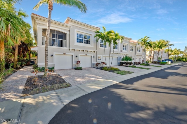 view of front of house featuring stucco siding, a tile roof, decorative driveway, and a garage