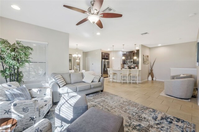 living area featuring light tile patterned floors, visible vents, ceiling fan with notable chandelier, and recessed lighting